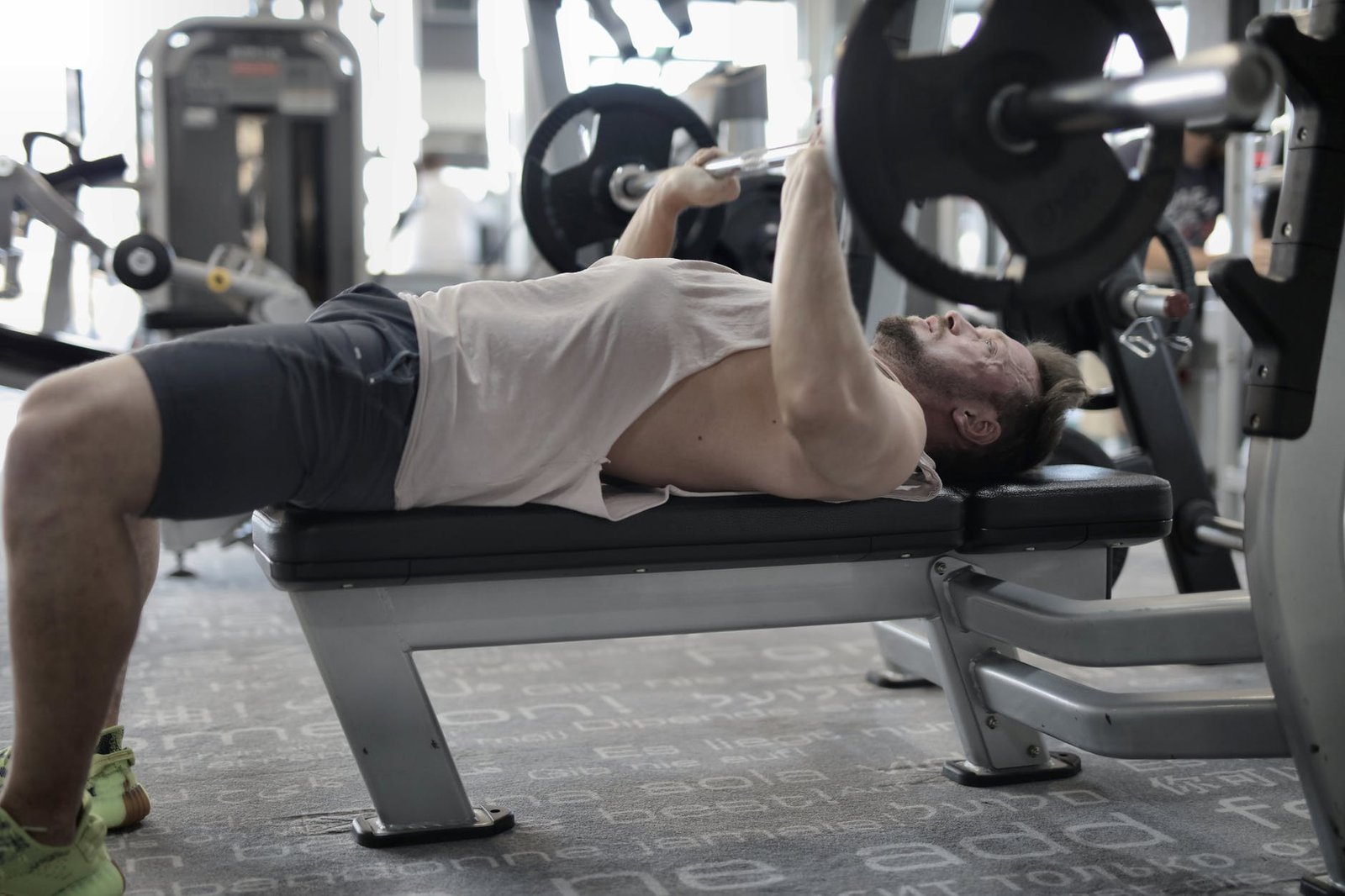 strong sportsman working out on bench in modern gym